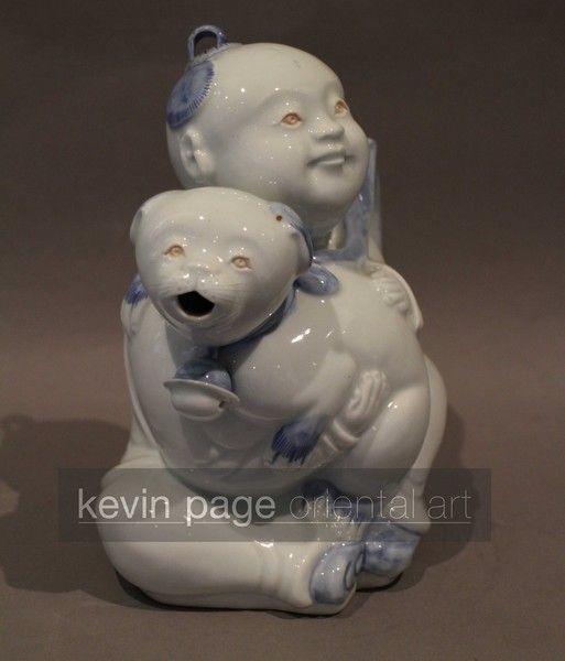 A japanese hirado teapot in the form of a boy with a dog